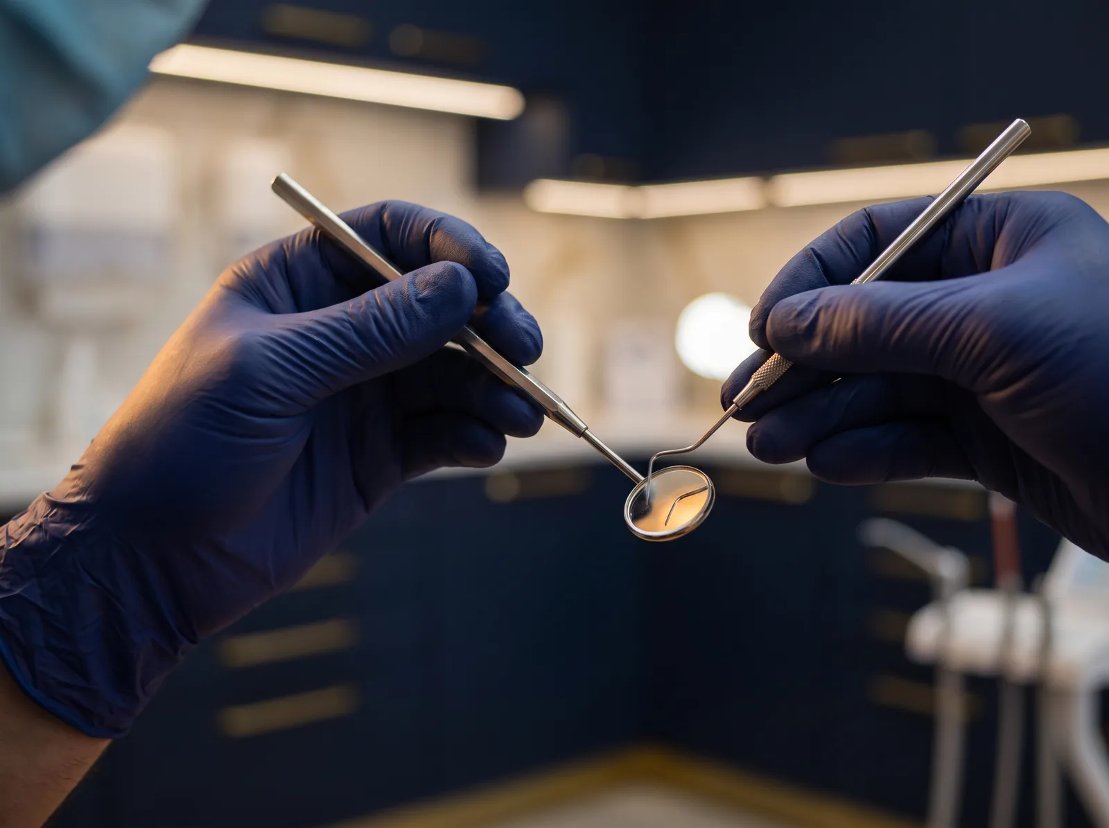 Mani di un dentista al lavoro con specchietto e sonda, dettaglio clinico