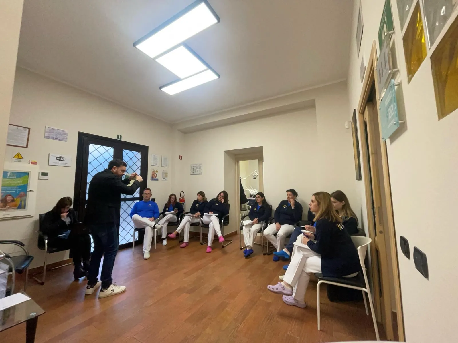 Federico Vecchio in piedi mentre forma il team di uno studio, seduto in sala d'attesa